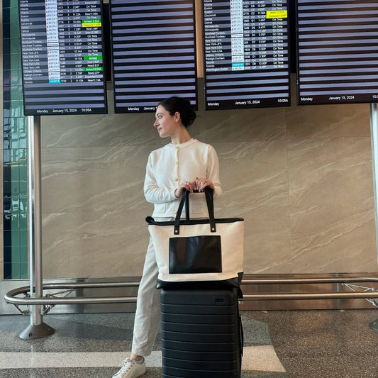 Woman at airport with large insulated tote bag on suitcase, travel chic lunch bag style