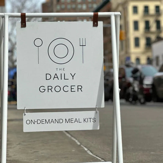Street sign for The Daily Grocer on-demand meal kits with plate and cutlery icon.