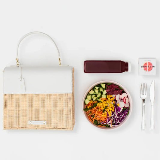Stylish woven lunch tote with fresh salad, juice, and utensils for healthy on-the-go meals
