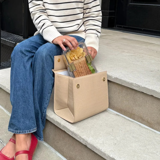 Beige textured lunch bag with sandwich and chips, styled for work or travel