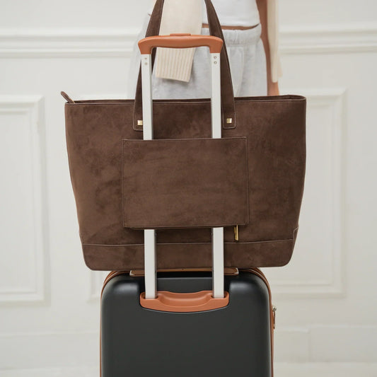 Chic brown vegan leather tote bag on rolling suitcase, perfect for travel and work style