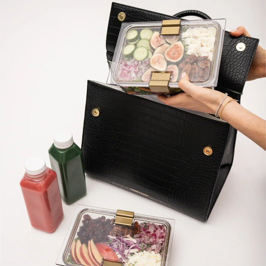 Chic black vegan leather lunch tote with salads in clear containers and two juice bottles