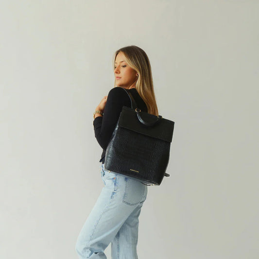 Woman wearing black croc-texture vegan leather backpack, stylish for work or travel