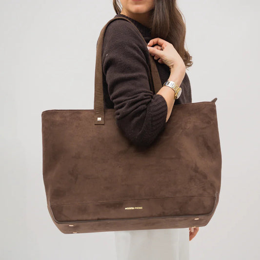 Woman carrying large brown vegan leather tote bag with gold details, stylish and insulated
