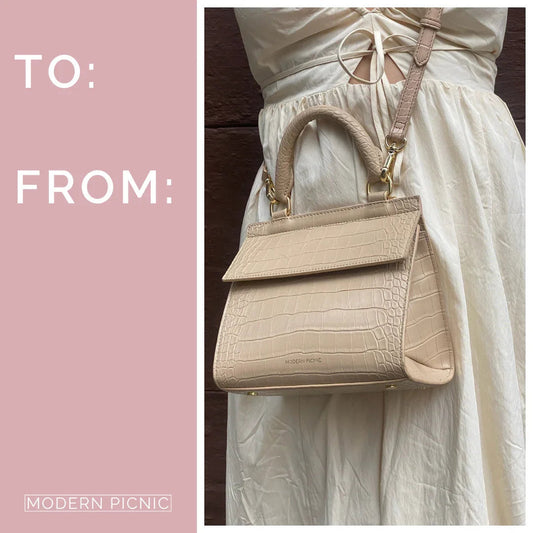 Beige croc-texture vegan leather handbag with top handle and shoulder strap, styled with cream dress