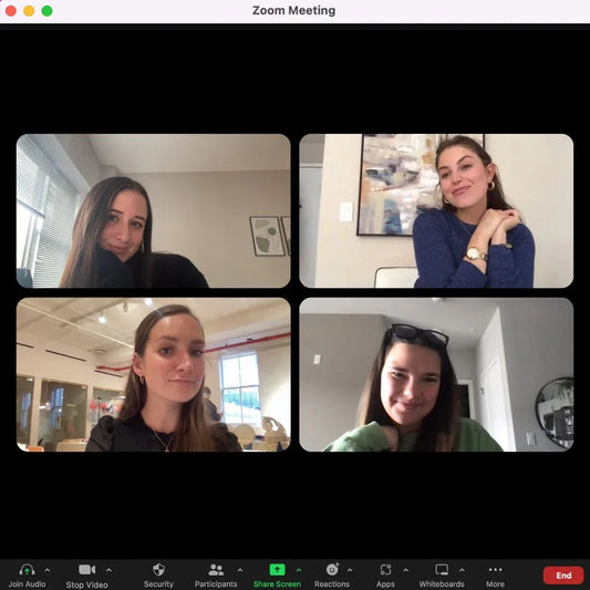 Four women in a Zoom meeting, smiling during virtual work session
