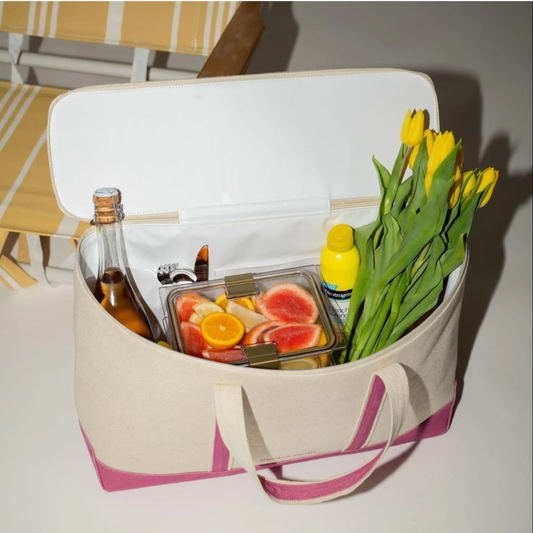 Chic insulated tote bag packed with drinks, fresh fruit, sunscreen, and yellow tulips for lunch.