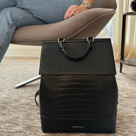 Black croc-texture vegan leather backpack with top handle, styled for work or travel