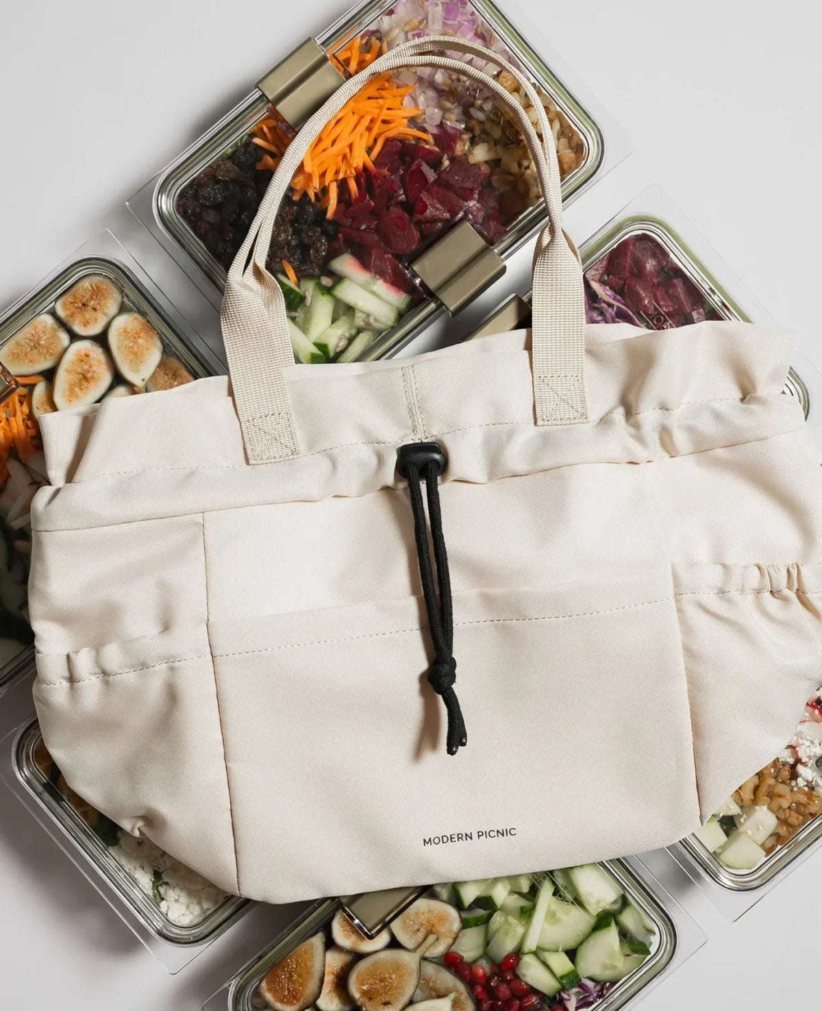 Cream insulated vegan leather lunch tote bag surrounded by healthy meal prep containers.