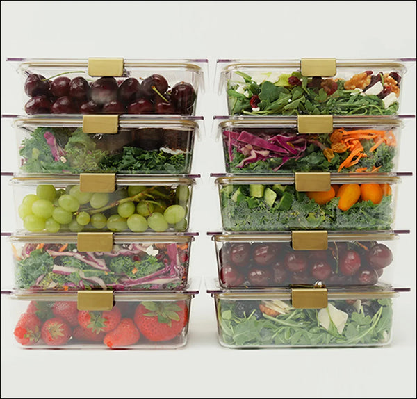 Stacked clear meal prep containers with fresh salads, fruits, and veggies for healthy lunches
