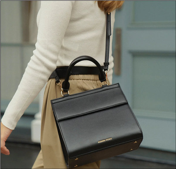 Black vegan leather lunch tote with top handle and shoulder strap, stylish for work or travel