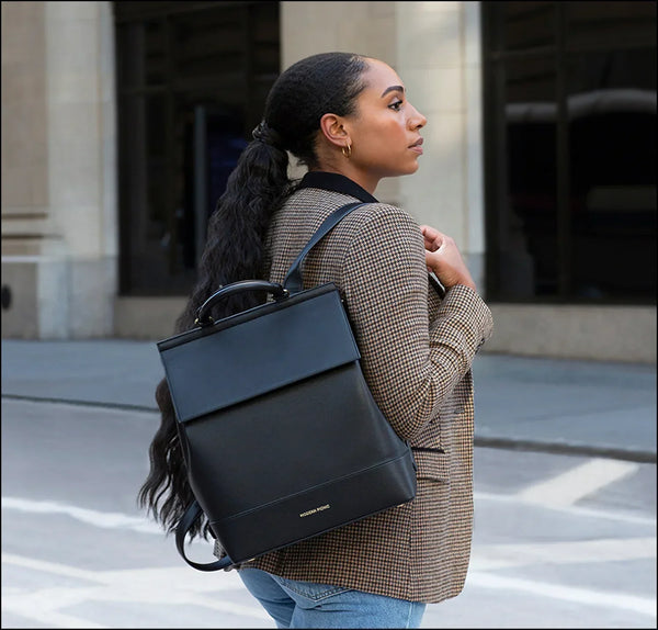 Stylish black vegan leather backpack for work, travel, and everyday use, worn by woman in city setting