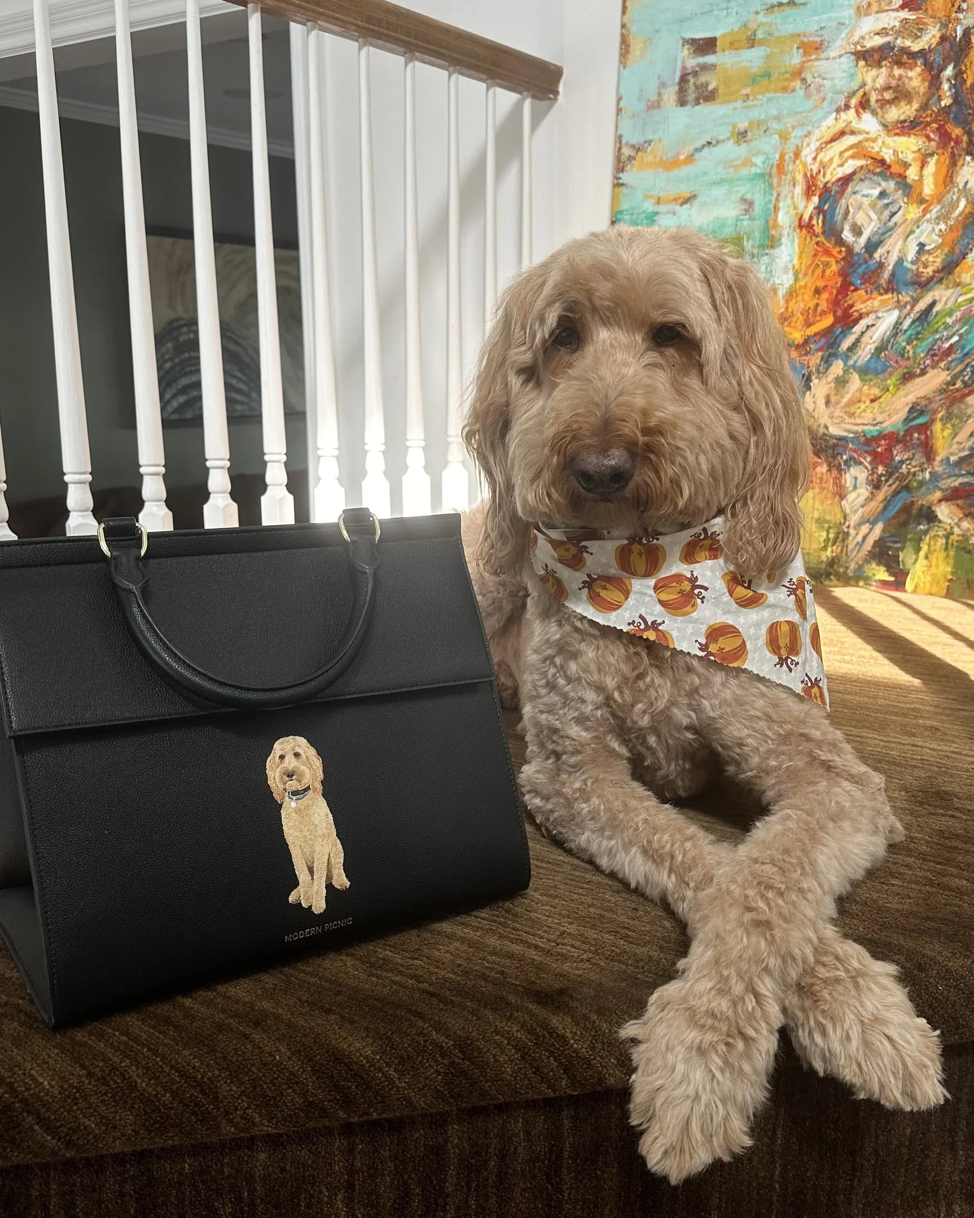 Goldendoodle dog with printed bandana beside black insulated lunch tote bag featuring dog illustration