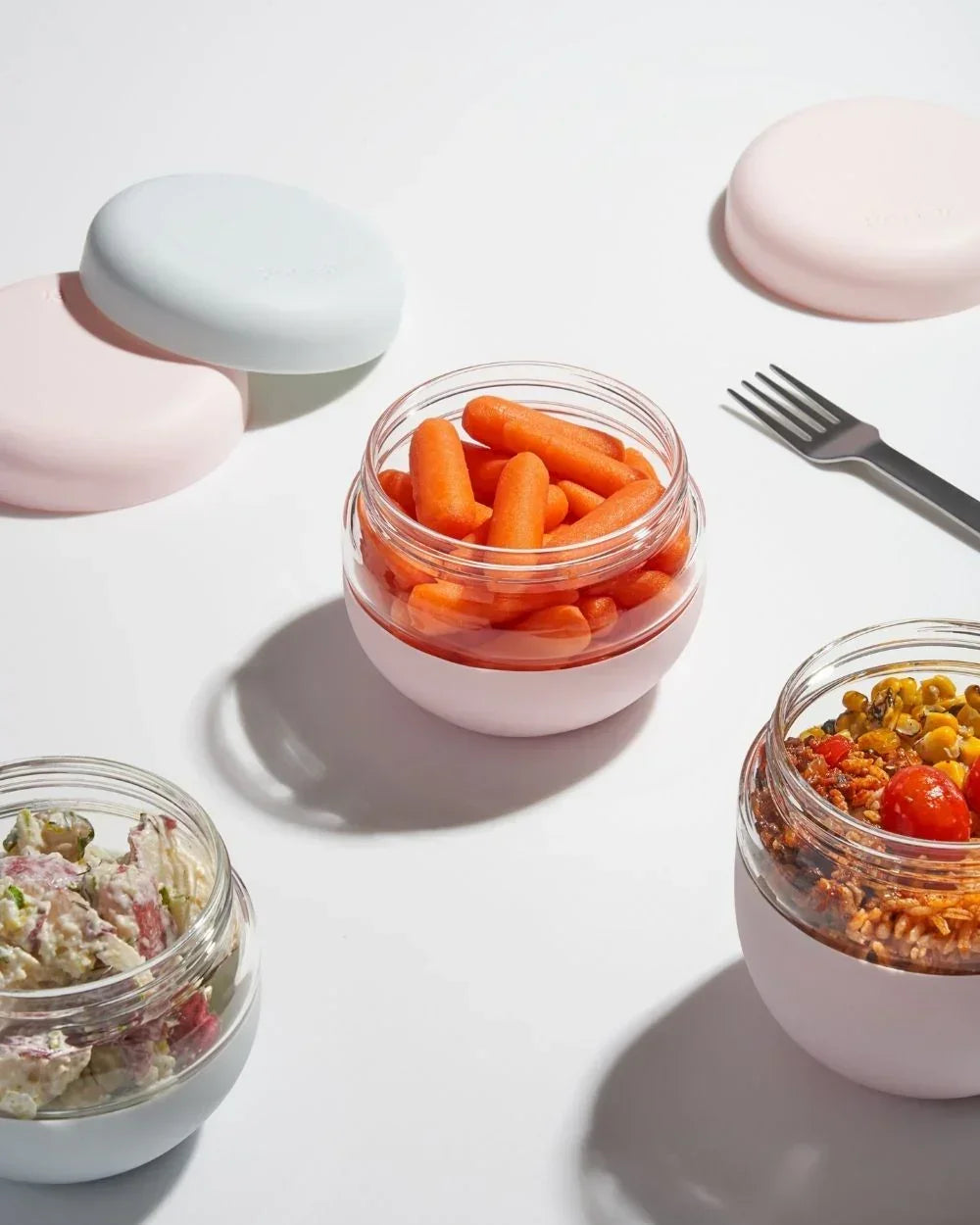 Set of chic insulated food containers with healthy snacks and salads on a white background