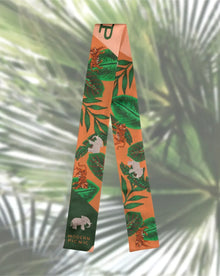 Tropical-themed scarf with tigers, elephants, and green leaves on orange background, styled for modern picnic vibes.