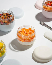 Assorted snacks in insulated glass food jars with pastel lids, perfect for lunch or meal prep