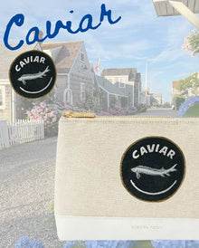 Cream canvas pouch with 'Caviar' fish patch, coastal backdrop — stylish lunch bag for work or travel
