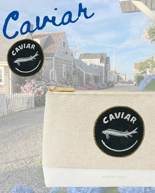 Cream canvas pouch with 'Caviar' fish patch, coastal backdrop — stylish lunch bag for work or travel