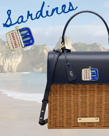 Navy and wicker tote bag with sardine can charm, beach backdrop, stylish picnic accessory