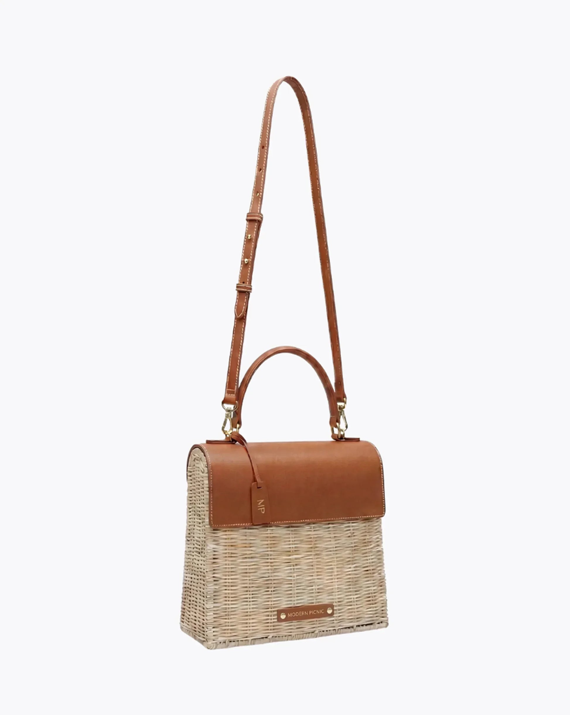 Woven straw tote with brown leather accents and adjustable strap, perfect for stylish everyday use.