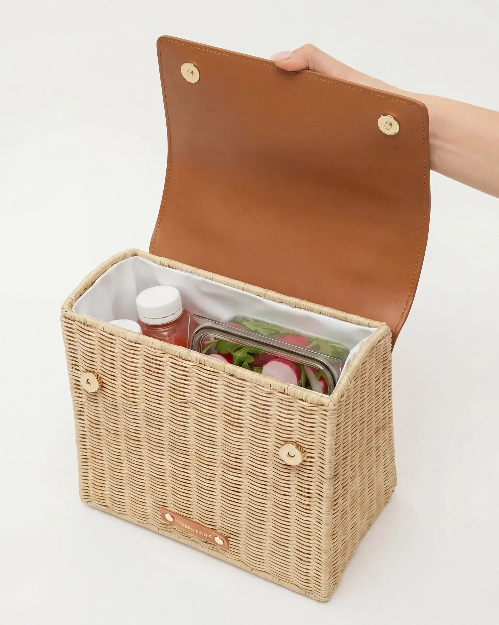 Woven picnic basket with insulated interior holding salad and drinks, perfect for stylish outdoor meals.