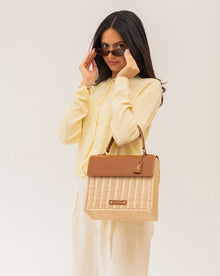 Stylish woman holding a chic woven tote bag with vegan leather accents, perfect for work or travel.