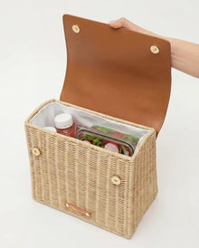 Woven picnic tote with insulated interior holding food and drinks, perfect for stylish outdoor meals.