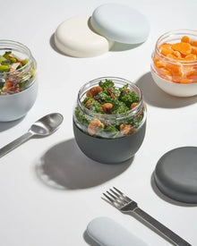 Modern insulated glass lunch jars with salads and fruit, reusable silverware, minimalist style