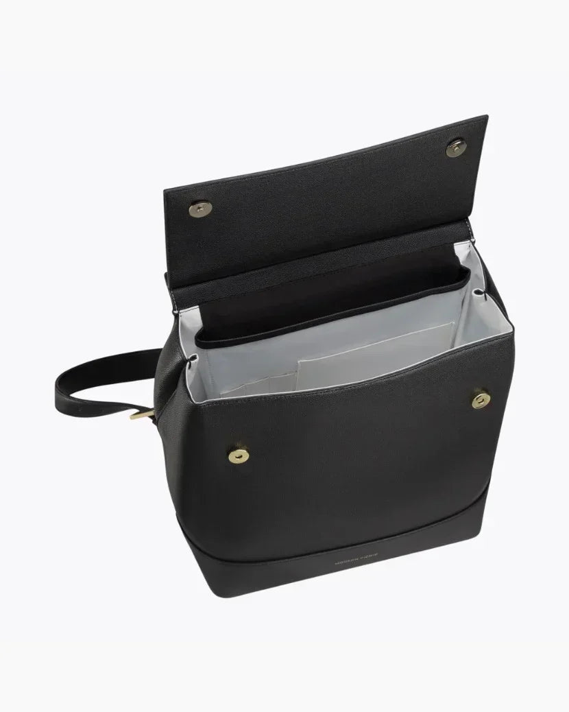 Top-down view of the open black Modern Picnic vegan leather backpack. The image highlights the contrast white insulated interior designed to keep food cool, along with the internal slip pockets and the gold-tone magnetic snap closures on the flap and body.