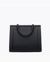 A straight-on product shot of the back of a black vegan leather handbag. The image clearly shows the curved top handle, gold-tone hardware, and the subtle stitched outline indicating the exterior slip pocket.