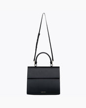 A product shot of a black handbag. The bag is shown with its long, adjustable shoulder strap extended and hanging from the gold-tone hardware, emphasizing its ability to be worn as a crossbody bag. The top handle and the subtle MODERN PICNIC logo are also visible.