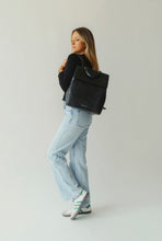 Woman modeling the stylish black crocodile-embossed backpack, showcasing its fashion and fit with blue jeans and a black long sleeve.