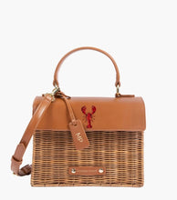 Front view of The Wicker Mini in Brown Wicker Lobster by Modern Picnic, featuring a hand-woven wicker exterior, brown vegan leather flap with a printed red lobster, top handle, adjustable strap, and gold hardware.