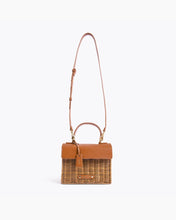 Brown Wicker Mini Lunchbox by Modern Picnic shown with full-length adjustable crossbody strap, featuring a hand-woven wicker exterior, brown vegan leather flap, top handle, and gold hardware.