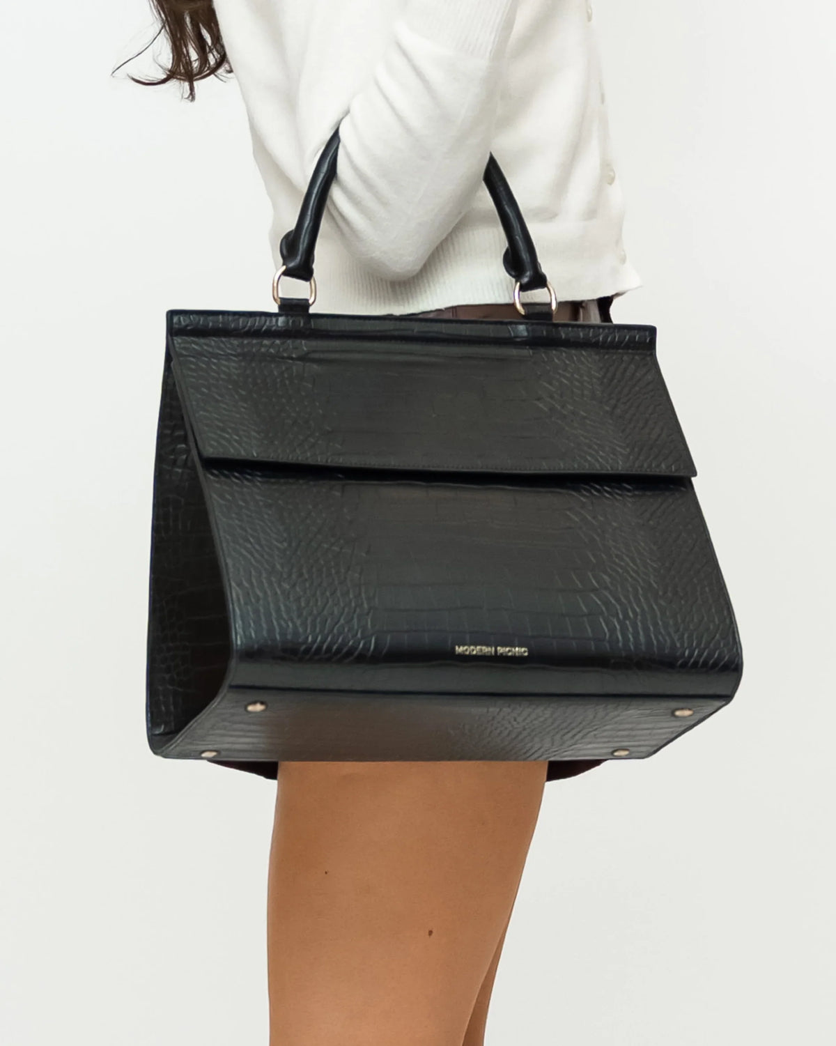 Woman holding a black vegan leather textured insulated lunch bag with top handles.