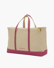 A large, structured canvas tote bag/cooler is shown in a three-quarter view against a white background. The body is natural beige canvas, contrasted with bright pink trim along the bottom base, the reinforced carry handles, and the vertical stripes down the sides. The bag has a gold zipper closure and a small "MODERN PICNIC" logo on the front.