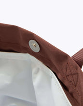 Close-up of a brown fabric with a button and logo on a white background