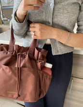 Person holding a brown bag with 'Modern Picnic' branding in a kitchen setting cobranded with FabFitFun