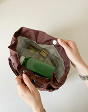 Brown lunchbox with a green juice inside, held by hands against a neutral background cobranded with FabFitFun