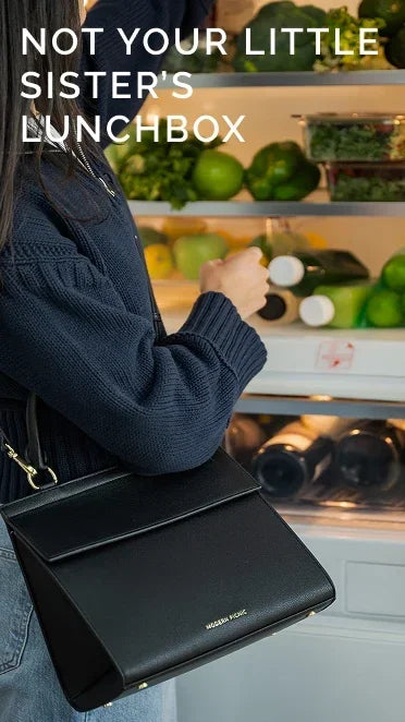 Woman carrying a chic black vegan leather lunch bag in front of an open refrigerator.