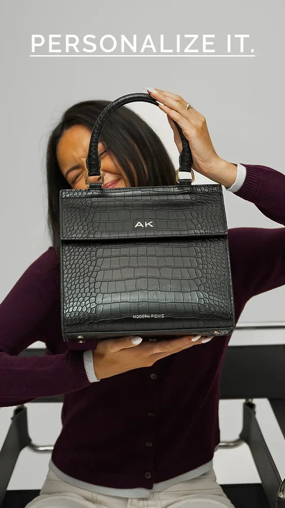 Woman holding a personalized black crocodile embossed vegan leather lunch tote bag with AK initials.