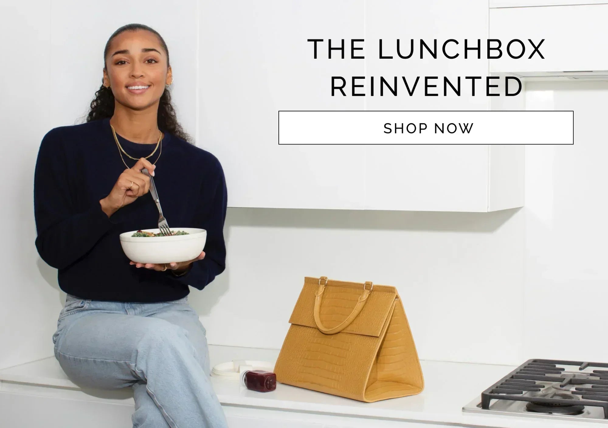 Woman eating salad beside stylish insulated lunch bag in modern kitchen