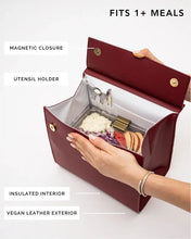Structured red smooth luncher is shown open, revealing a silver insulated interior containing a food container and labeled features like the magnetic closure, utensil holder, and vegan leather exterior.