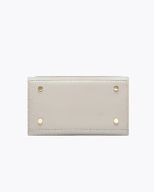 Bottom view of the Kids Mini Stone bag by Modern Picnic, showing the stone-colored vegan leather base with four gold metal feet, clean stitching, and a structured rectangular design displayed on a white background.