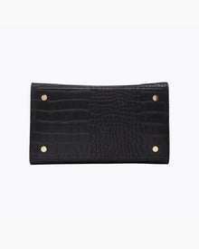 A close-up view of the bottom of the black handbag, showing the flat base with a crocodile-embossed texture. The base is protected by four small gold metal feet (studs).