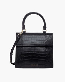 A front-facing studio shot of a structured black top-handle handbag. The bag is fully covered in a crocodile-embossed texture and features a clean flap closure, a detachable matching shoulder strap, and gold hardware. The logo "MODERN PICNIC" is subtly visible in gold near the bottom.