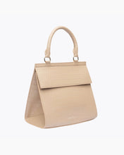 A three-quarter studio shot of a structured, light beige top-handle handbag. The bag features an all-over crocodile-embossed texture, a curved top handle, a prominent flap closure, and a gold "MODERN PICNIC" logo near the bottom front edge.