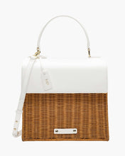 A front-facing studio shot of a structured small top-handle handbag with a two-tone design. The top flap, handle, and adjustable shoulder strap are smooth white vegan leather, while the bottom half is made of natural brown woven wicker. The bag includes a white hang tag with gold "MP" initials and a small white logo plaque on the wicker.