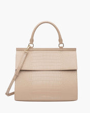 A front-facing studio shot of a structured top-handle handbag in a light cream color. The main body and flap closure feature a crocodile-embossed texture. The bag has a matching top handle, a detachable shoulder strap, and gold hardware. The logo, "MODERN PICNIC," is subtly embossed near the bottom.