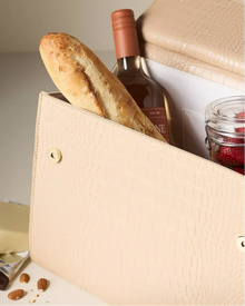 Cream croc-embossed insulated lunch bag with baguette, wine, jar of berries, and cheese inside